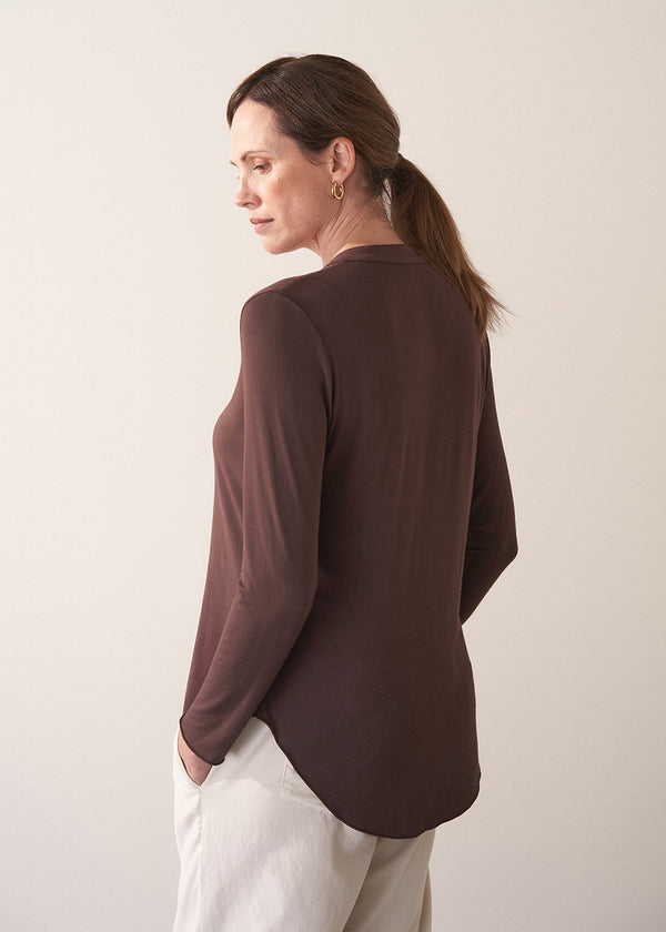 Woman wearing a brown long-sleeve jersey top against a plain background