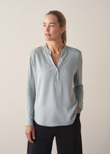 Woman wearing long sleeve pale blue top with black wide leg trousers