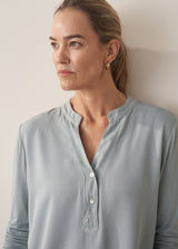 Woman wearing long sleeve pale blue top with black wide leg trousers