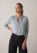 Woman wearing long sleeve pale blue top with black wide leg trousers