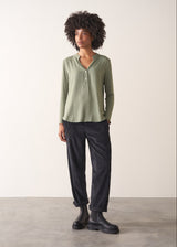 Woman wearing a green long-sleeve t-shirt against a white background