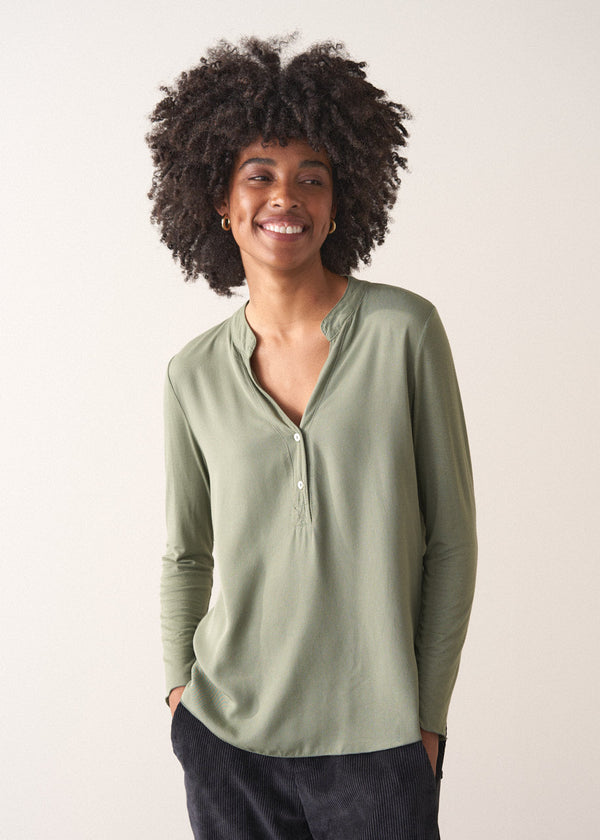 Woman wearing a green long-sleeve t-shirt against a white background