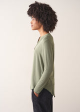Woman wearing a green long-sleeve t-shirt against a white background
