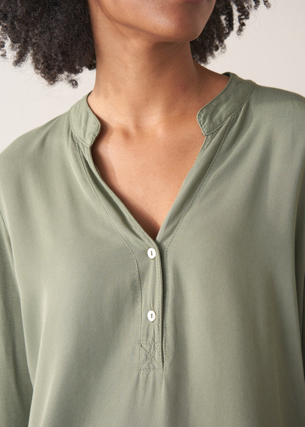 Woman wearing a green long-sleeve t-shirt against a white background