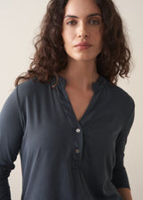 Woman wearing dark grey long sleeve top and white barrel leg jeans