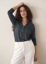 Woman wearing dark grey long sleeve top and white barrel leg jeans