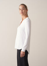 Woman wearing white long sleeve top with black trousers