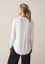 Woman wearing white long sleeve top with black trousers