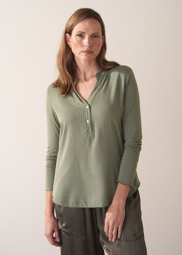 Woman wearing a moss green long-sleeve jersey top against a plain background