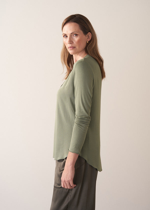 Woman wearing a moss green long-sleeve jersey top against a plain background