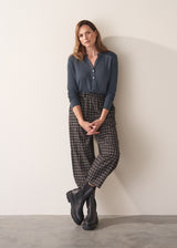 Woman wearing dark grey blue long sleeve jersey top against a plain background