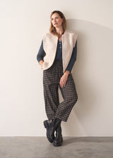 Woman wearing dark grey blue long sleeve jersey top against a plain background