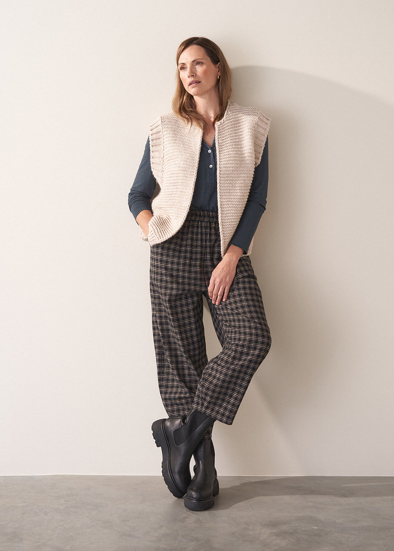 Woman wearing dark grey blue long sleeve jersey top against a plain background