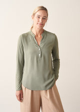 Woman wearing a sage green long sleeve top with beige wide leg cropped trousers