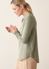 Woman wearing a sage green long sleeve top with beige wide leg cropped trousers