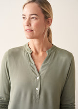Woman wearing a sage green long sleeve top with beige wide leg cropped trousers
