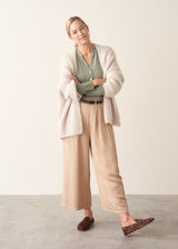 Woman wearing a sage green long sleeve top with beige wide leg cropped trousers