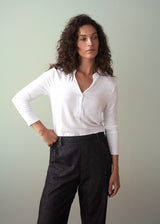 Woman wearing a long sleeve white top with button detail