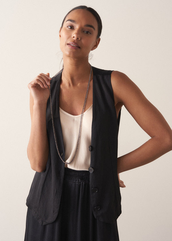 Model wears an ultra-long, fine gold chain necklace adorned with twinkling silver beads