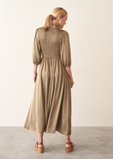 A woman wearing a light khaki green olive satin midi dress with smocked detail and ruffle collar