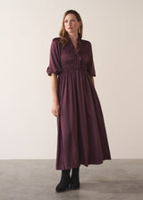 Woman wearing a plum sati midi dress standing against a plain background
