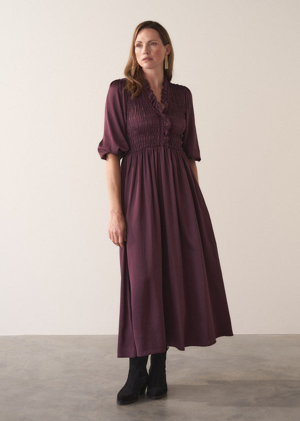 Woman wearing a plum sati midi dress standing against a plain background