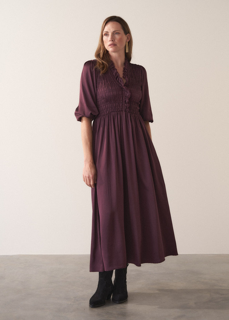 Woman wearing a plum sati midi dress standing against a plain background