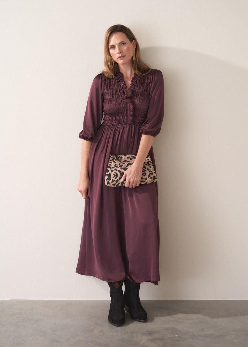 Woman wearing a plum sati midi dress standing against a plain background