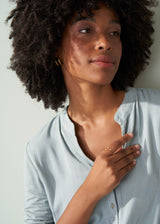 Model wearing open centre adjustable gold bubble ring with blue blouse
