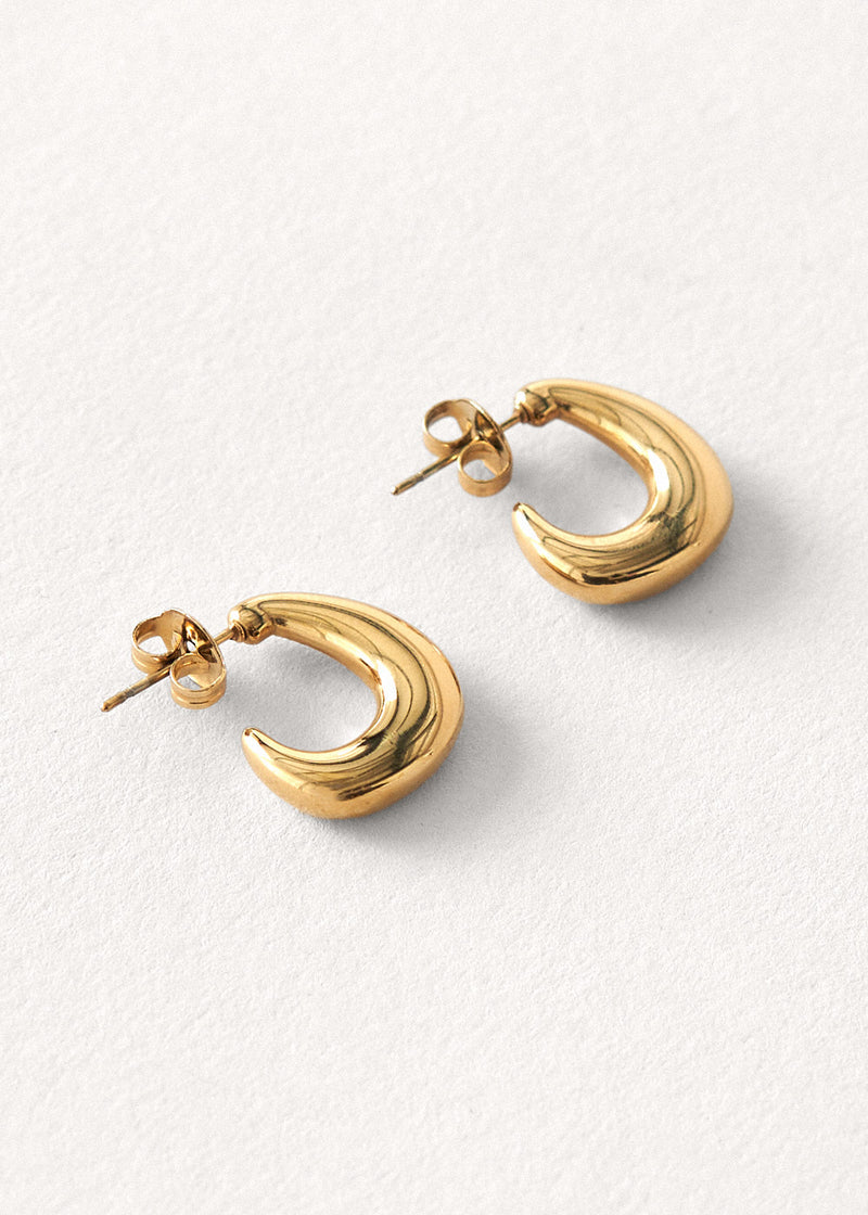 Gold structured hoop earrings on a beige background