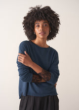 Person wearing a blue cashmere blend sweater and black wide leg trousers on a plain background