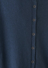 Person wearing a blue cashmere blend sweater and black wide leg trousers on a plain background