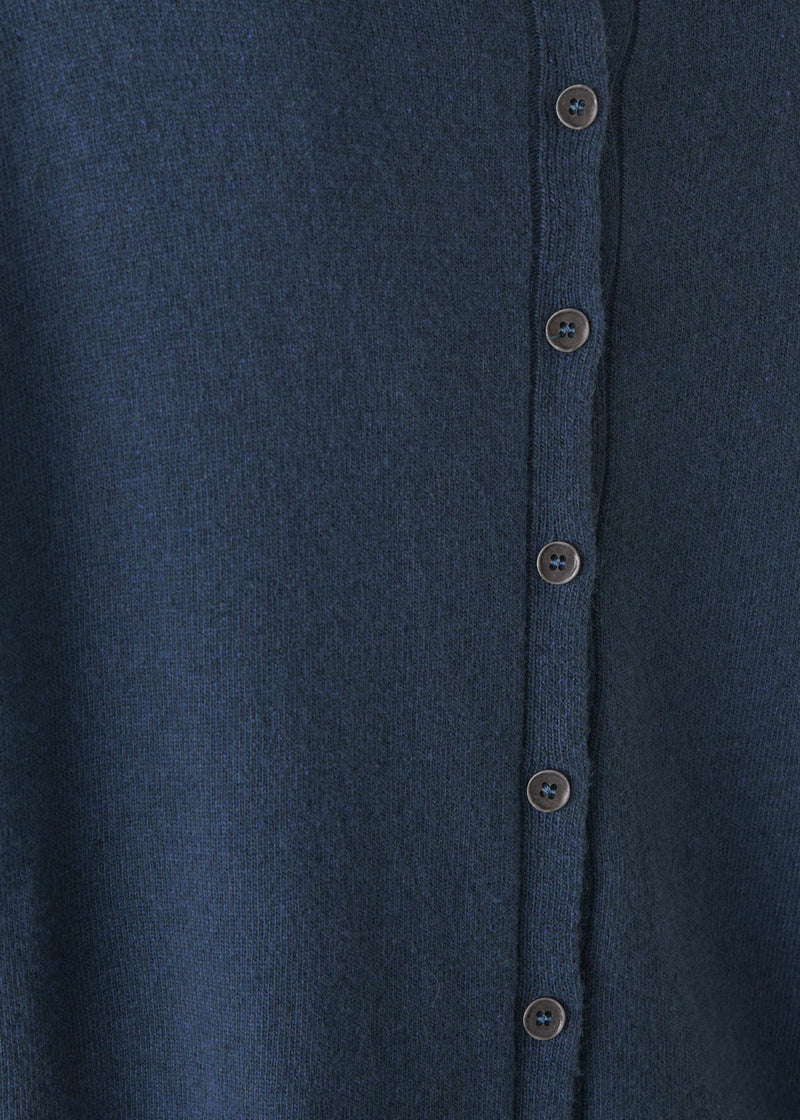 Person wearing a blue cashmere blend sweater and black wide leg trousers on a plain background