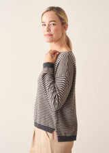 Woman wearing beige and grey stripe sweater with button back and beige cropped trousers