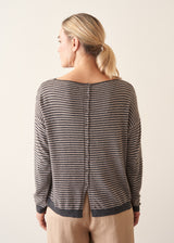Woman wearing beige and grey stripe sweater with button back and beige cropped trousers