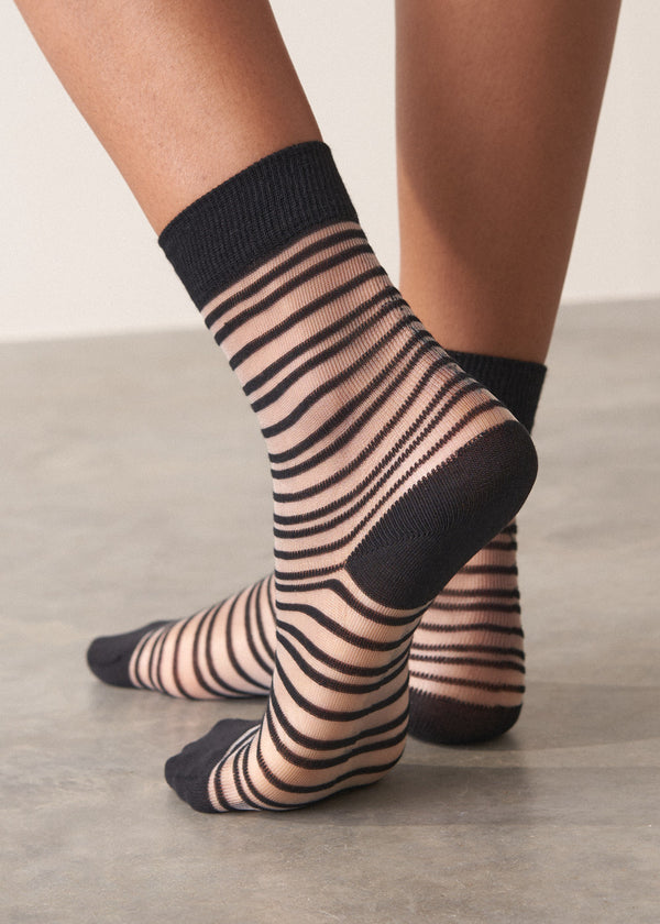 Person wearing black and sheer striped cotton blend ankle socks with ribbed hem
