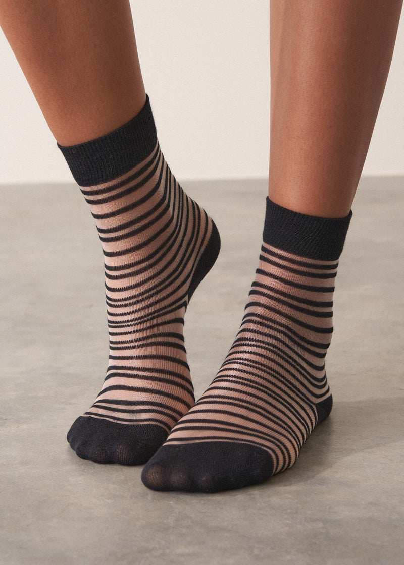 Person wearing black and sheer striped cotton blend ankle socks with ribbed hem