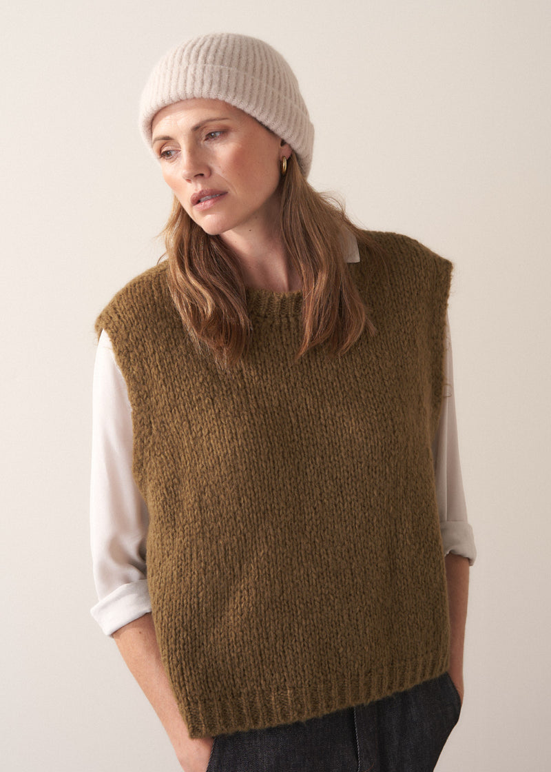 Woman wearing a cream, super soft, alpaca wool blend beanie hat, styled with khaki sweater and dark jeans