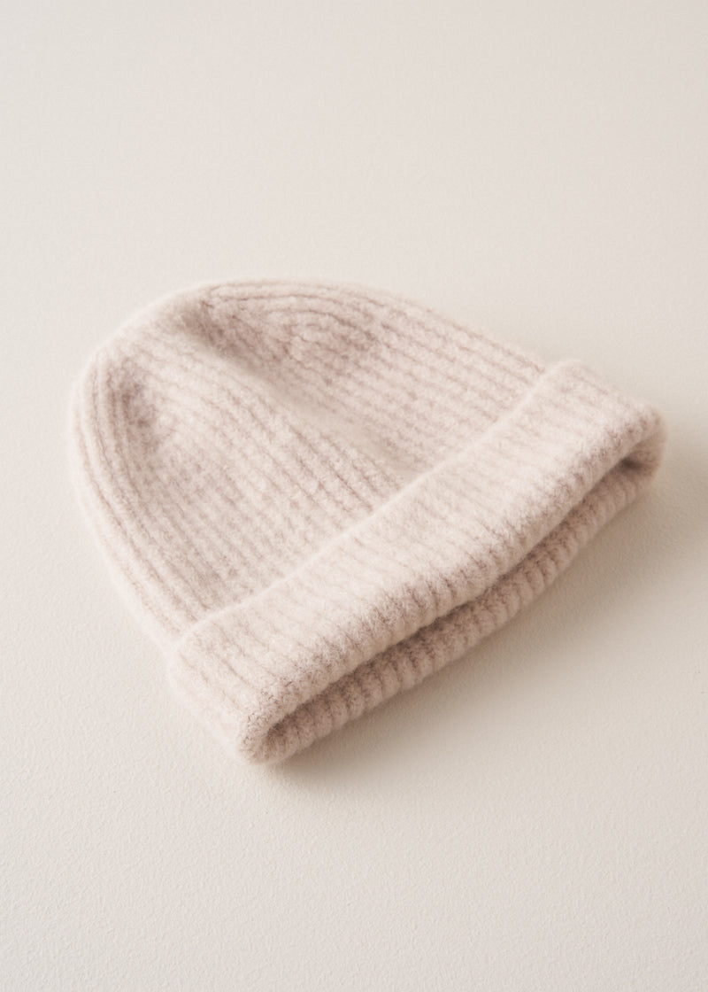 A super soft, alpaca wool blend cream beanie hat on beige background