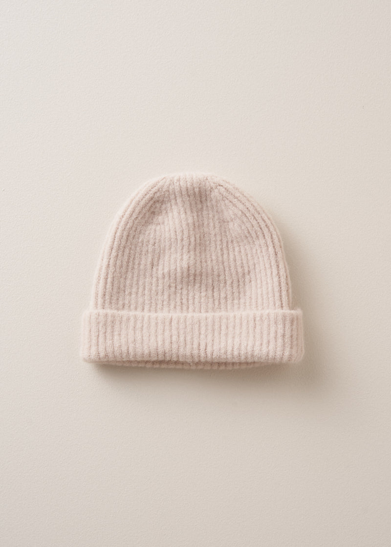A cream, super soft, alpaca wool blend beanie hat on beige background