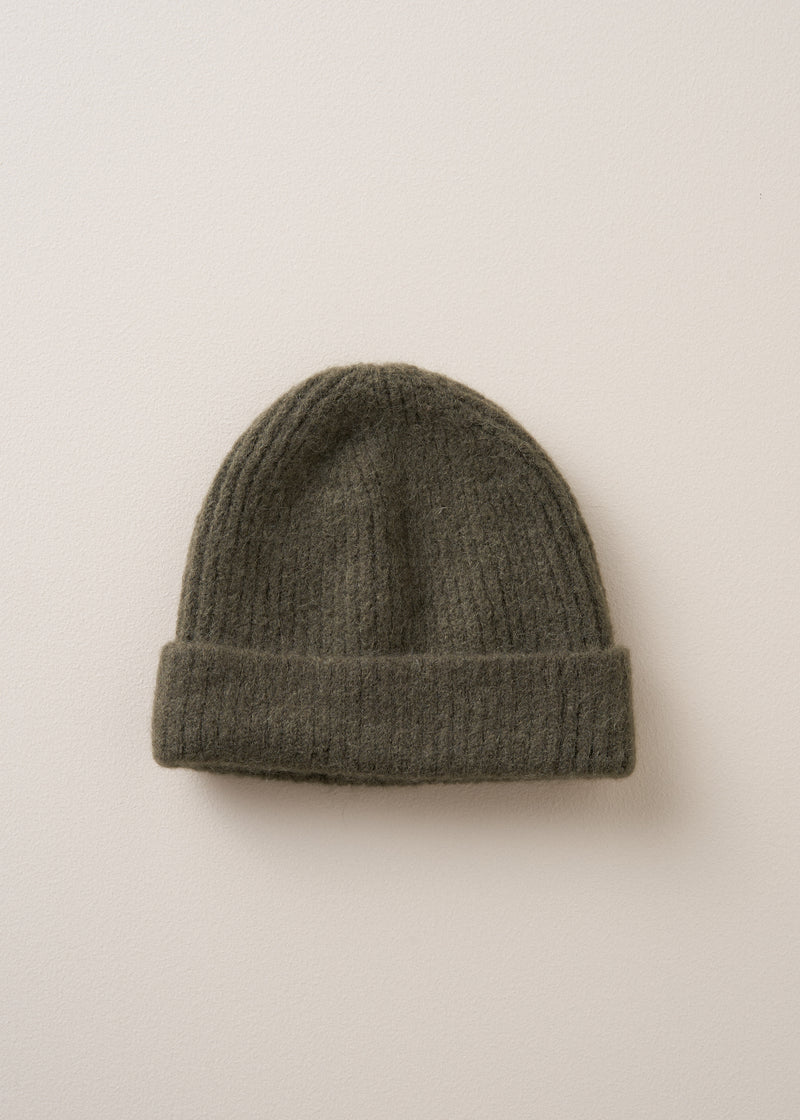 A super soft, alpaca wool blend beanie in khaki, on a beige background
