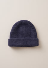An ultra soft, alpaca wool blend beanie hat in navy, on a beige background