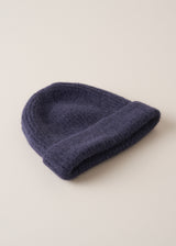 An ultra soft, alpaca wool blend beanie hat in navy, styled on a beige background