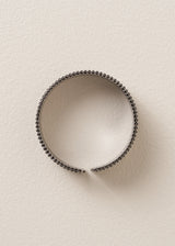 Side view of bracelet cuff with grey diamantes on beige background
