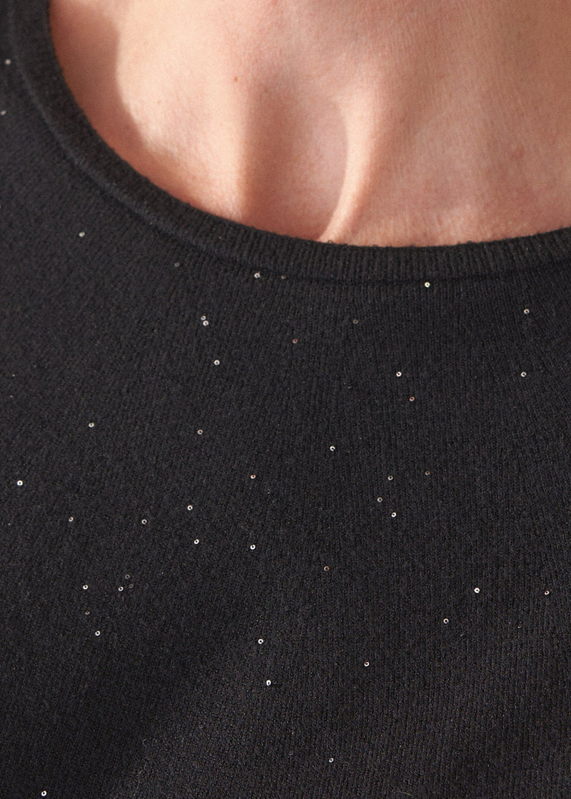 Close up of neckline on a black sweater with subtle sequin detail. 