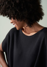 Close up of woman wearing a black sleeveless jumber against a neutral background