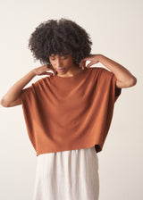 Woman wearing a light brown knitted top with a cream linen maxi skirt.