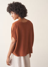 Woman wearing a light brown knitted top with a cream linen maxi skirt.