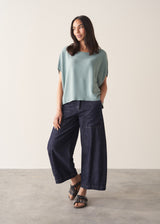 Woman wearing light sage sweater with blue jeans