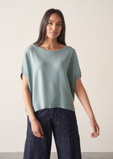 Woman wearing light sage sweater with blue jeans